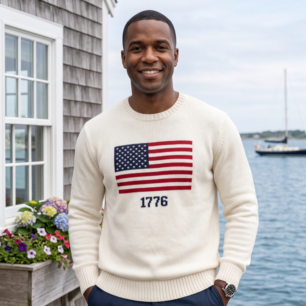 A close-up view of the white knit sweater highlighting the detailed 1776 and American flag graphic design and premium texture.