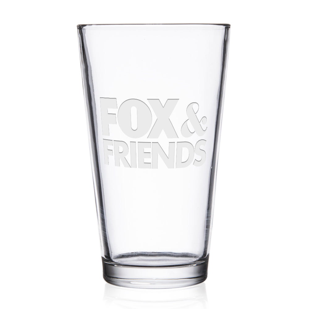 A personalized *FOX & Friends* laser engraved pint glass sitting on a clean wooden coaster in a bright, modern American kitchen.