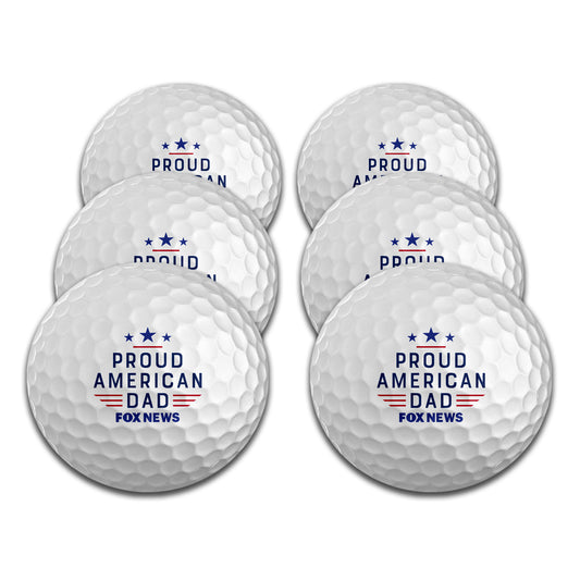A set of six white golf balls featuring the FOX News logo and Proud American Dad graphic, displayed in a clean American home setting.