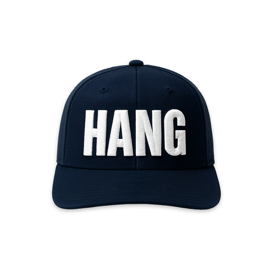 A navy blue FOX News Hannity HANG embroidered hat positioned on a clean wooden table in a brightly lit American home.