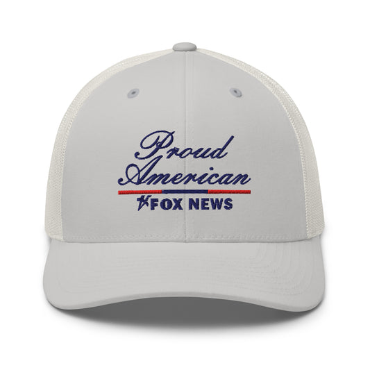 A Navy FOX News Proud American Trucker Hat resting on a clean wooden table in a brightly lit American living room.