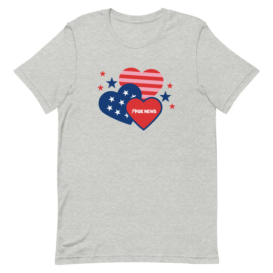 A Caucasian woman wearing the white *FOX News* Hearts Unisex T-Shirt in a clean, modern American living room, highlighting the crisp logo design.