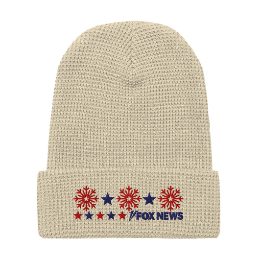 A person wearing the FOX News Holiday Snowflakes Beanie in a cozy American home setting.