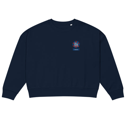 A modern American living room setting featuring the FOX News Proud American Mom embroidered sweatshirt folded neatly on a neutral-toned sofa.