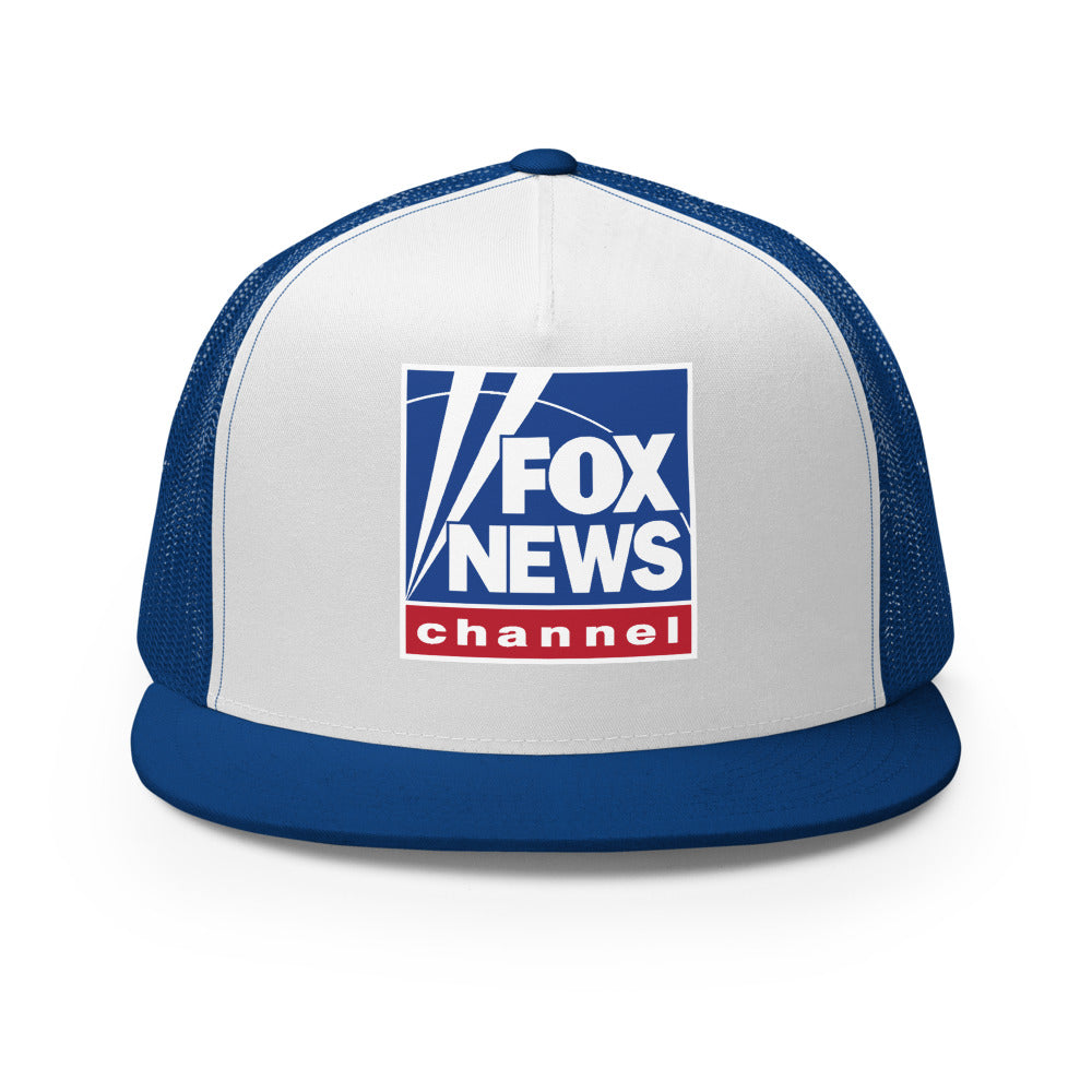 Side profile view of the royal blue and white FOX News trucker hat resting on a modern wooden surface.