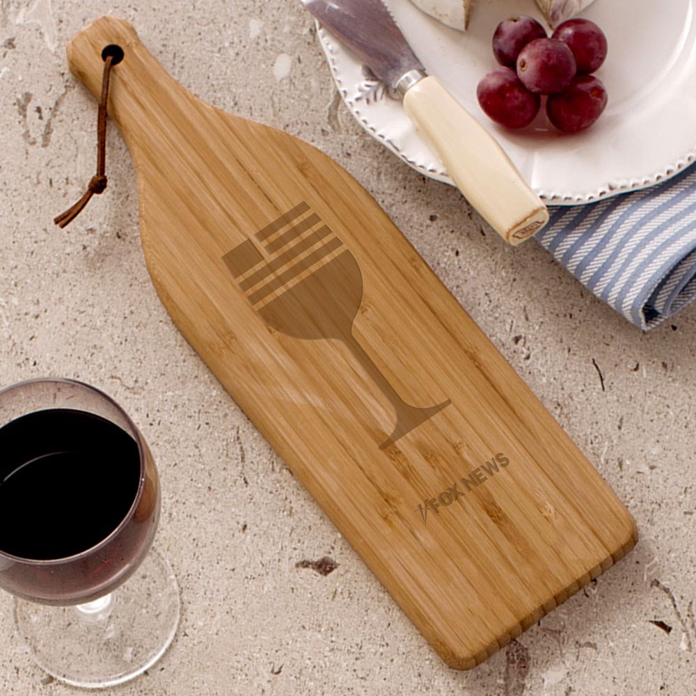 A large bamboo cutting board shaped like a wine bottle featuring the crisp *FOX News* logo etched on the front, set in a modern American kitchen.