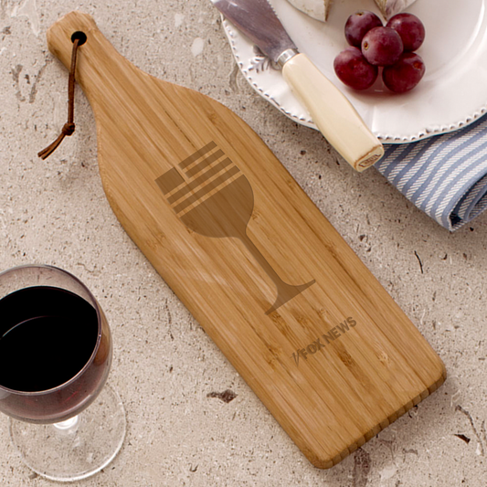 A large bamboo cutting board shaped like a wine bottle featuring the crisp *FOX News* logo etched on the front, set in a modern American kitchen.