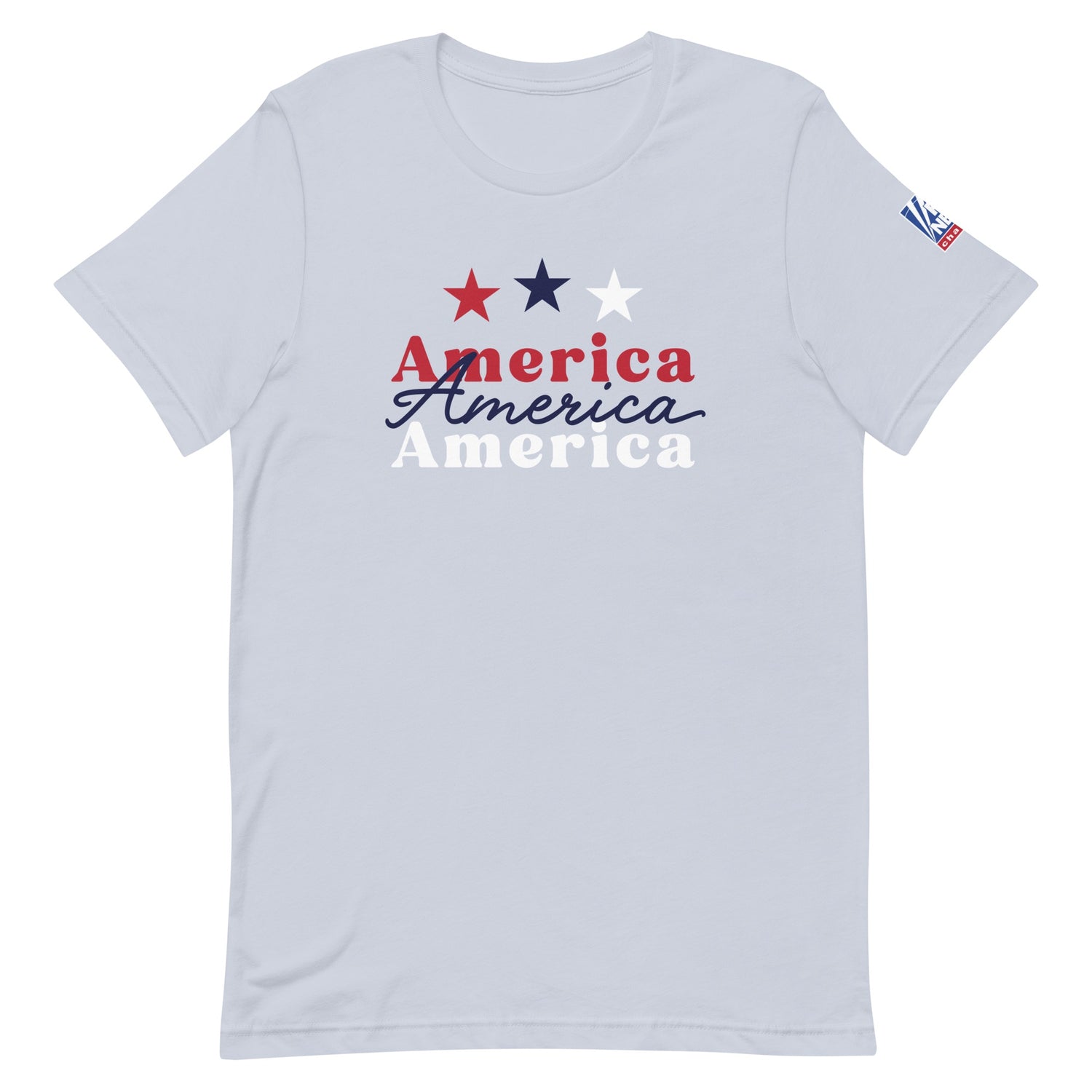 A proud American man wearing the light blue FOX News America t-shirt in a modern, sunlit American living room setting.
