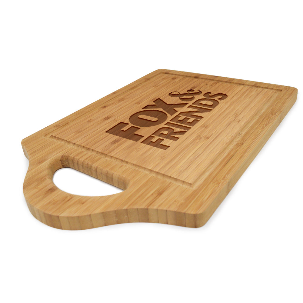 A wooden *FOX & Friends* cutting board with a handle, perfect for food preparation or as a charcuterie display piece.