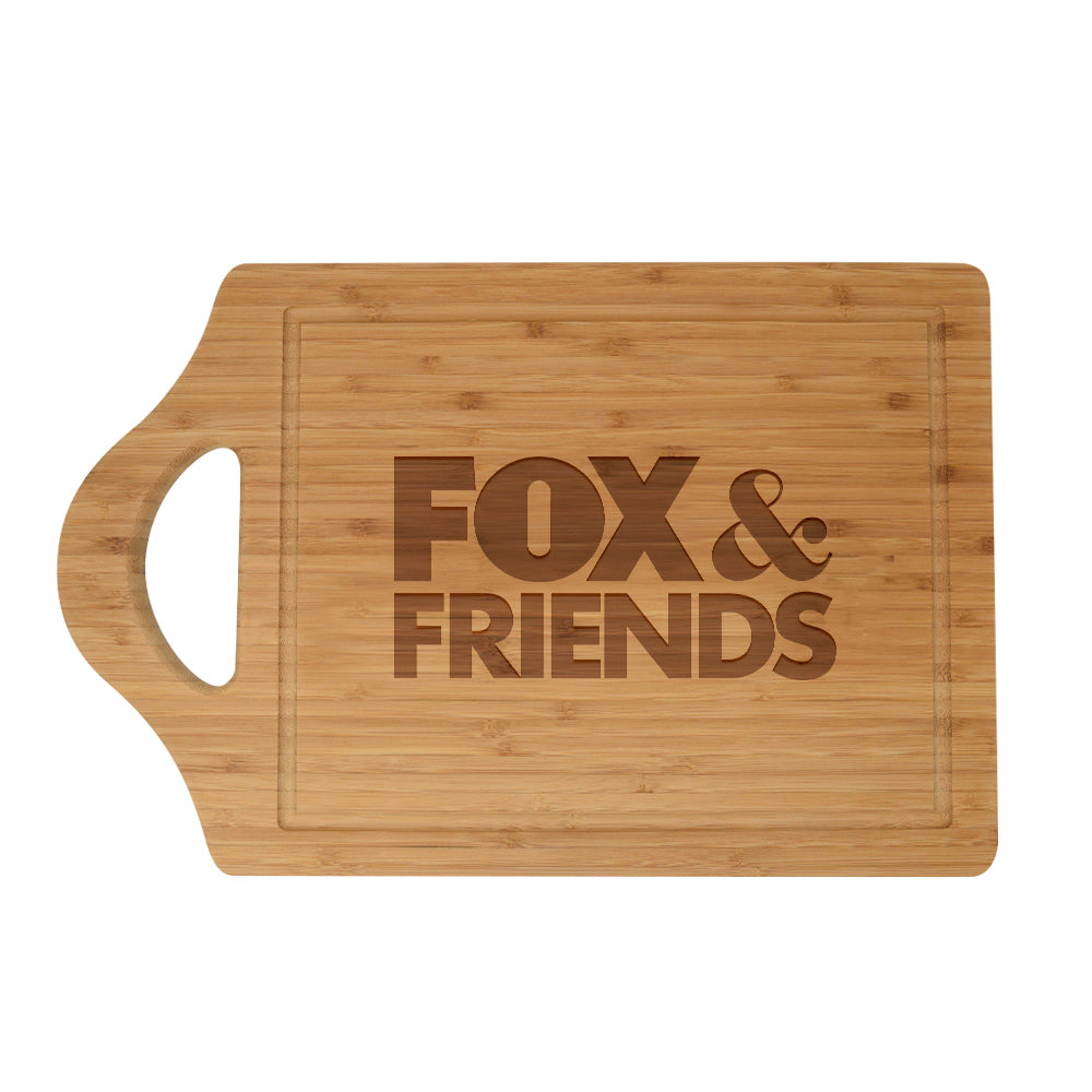 A *FOX & Friends* logo laser engraved cutting board displayed on a clean white kitchen counter in a suburban American home.