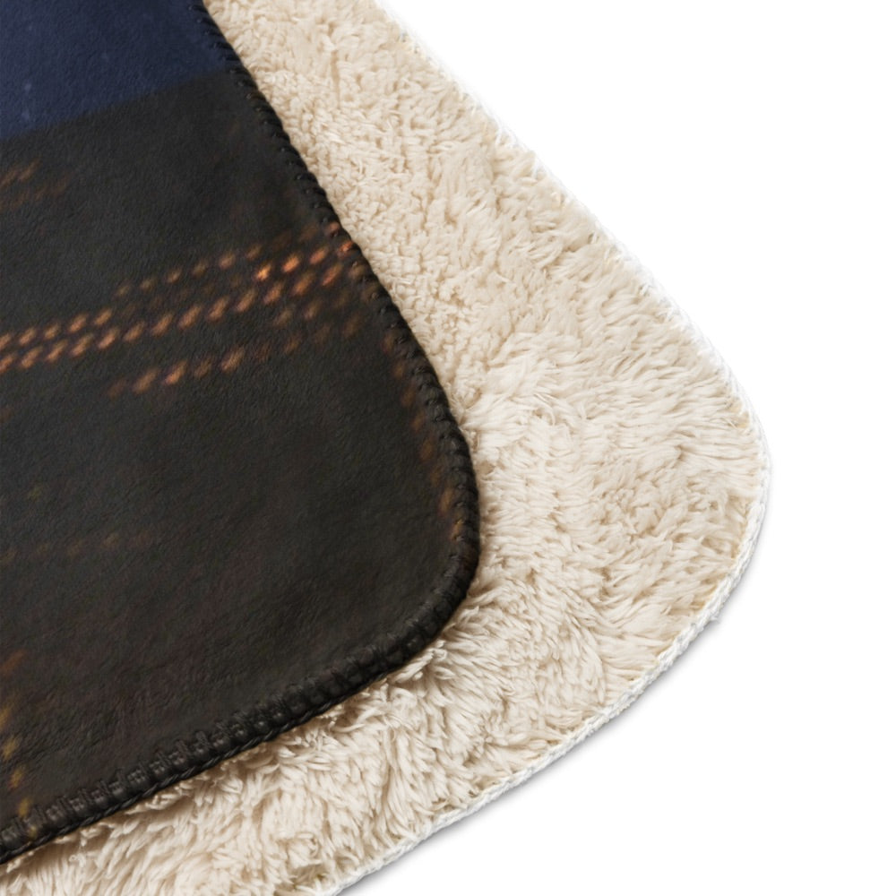 The Gutfeld! Logo Sherpa Blanket displayed in full view on a plush sofa, highlighting its generous sizing and bold branding.
