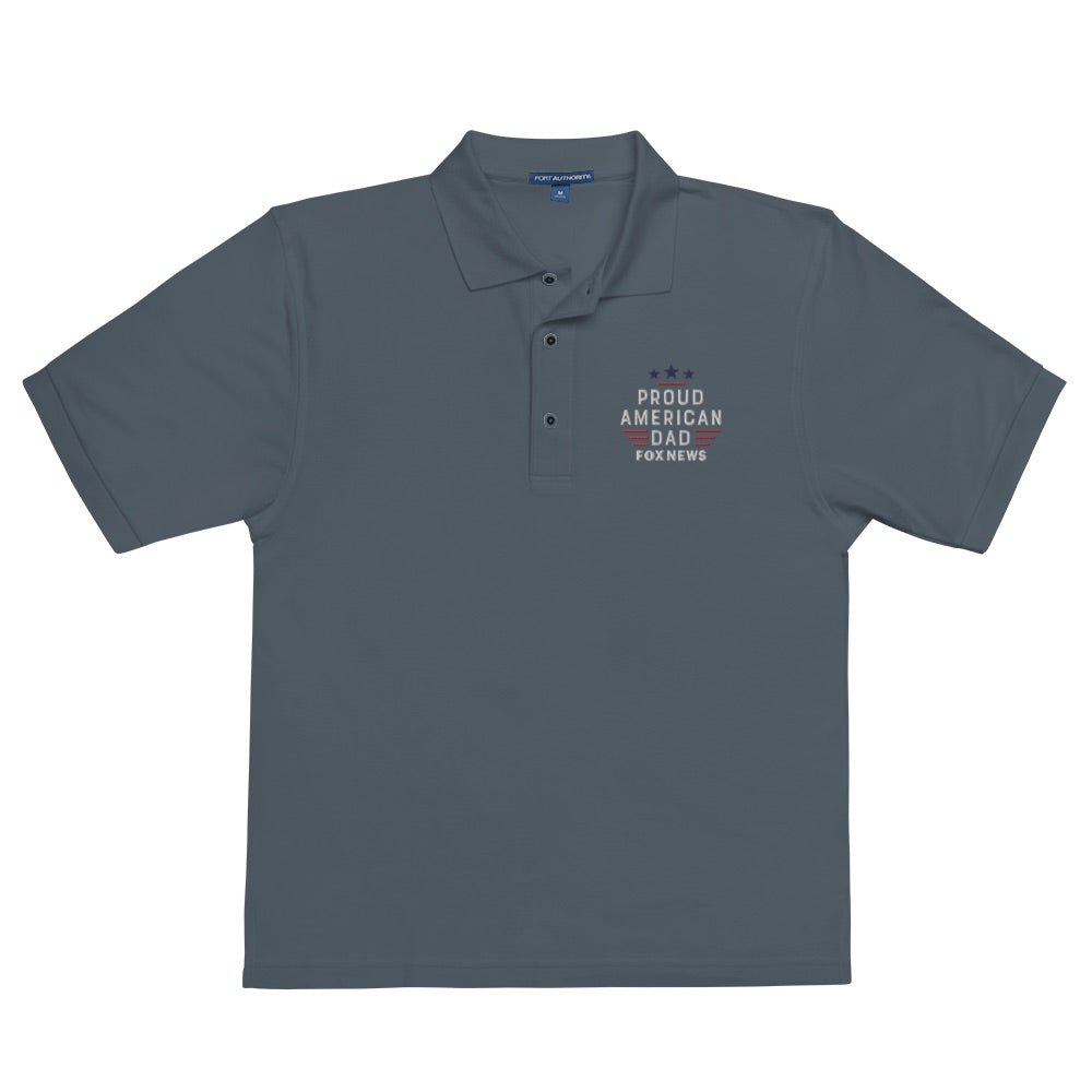 A modern American living room background showcasing the front view of the FOX News Proud American Dad embroidered polo shirt in Cool Heather.