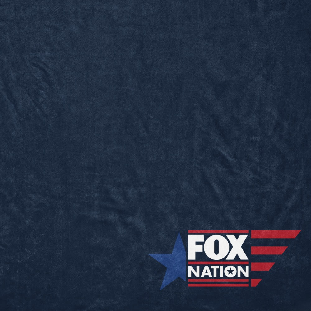 A warm and inviting armchair setup in a suburban American home with the FOX Nation logo blanket folded neatly across the seat.
