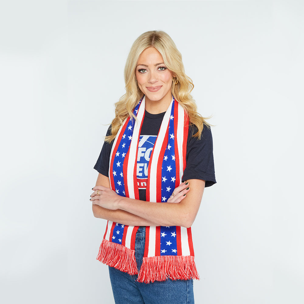 A FOX News Flag Scarf draped neatly on a wooden coat rack in a clean American home hallway, showing the red, white, and blue flag design and FOX News logo.