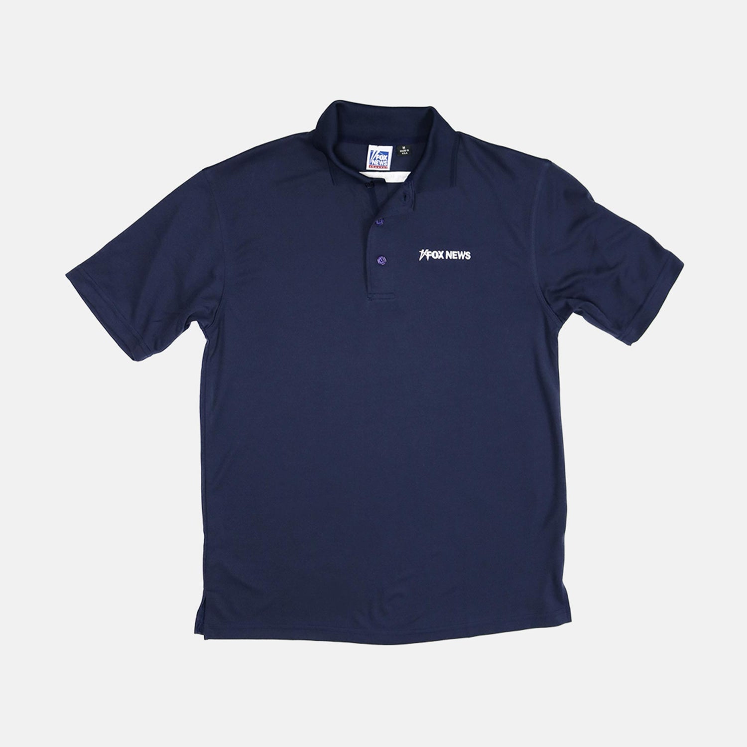 A man wearing a navy *FOX News* Men's Polo in a modern American backyard setting during a sunny morning.