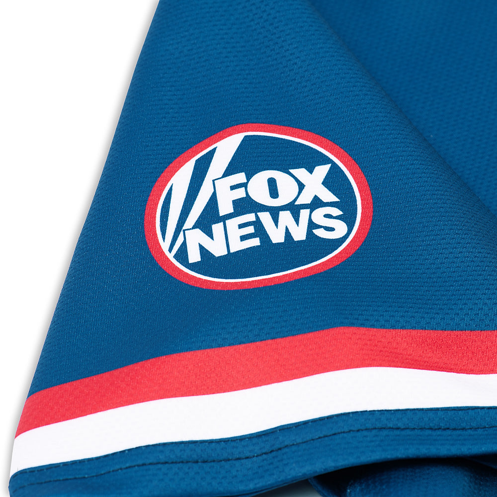 The FOX News Sports Baseball Jersey displayed on a shelf in a collector's room.