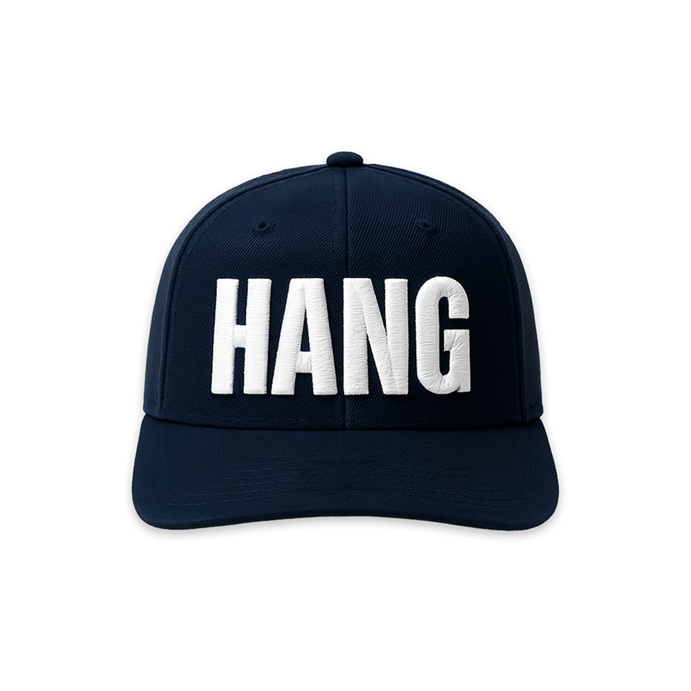 A navy blue FOX News Hannity HANG embroidered hat positioned on a clean wooden table in a brightly lit American home.