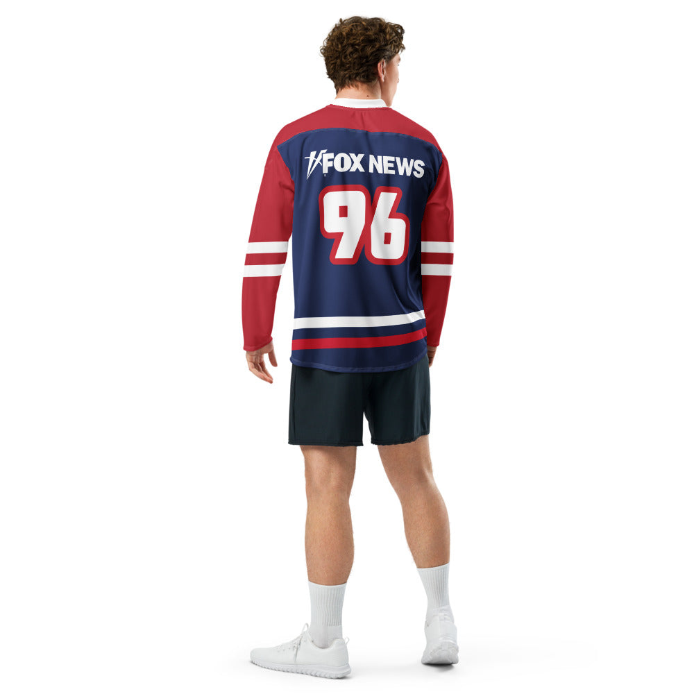 A female fan wearing the FOX News hockey jersey showing the bold patriotic design in a modern living room.