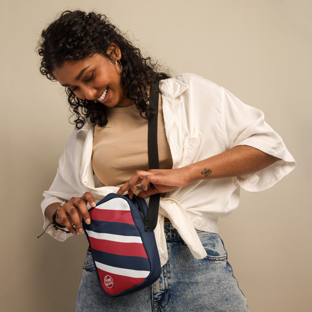 A person wearing the FOX News shoulder bag while walking in a suburban outdoor lifestyle context.
