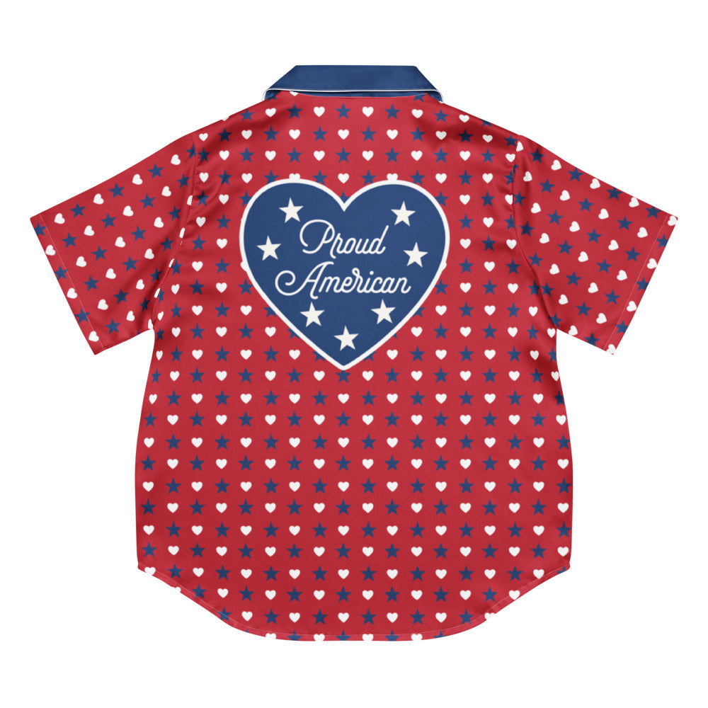 A woman relaxing in a clean, modern American living room wearing the FOX News Proud American Hearts And Stars women's short sleeve pajama top, smiling comfortably.