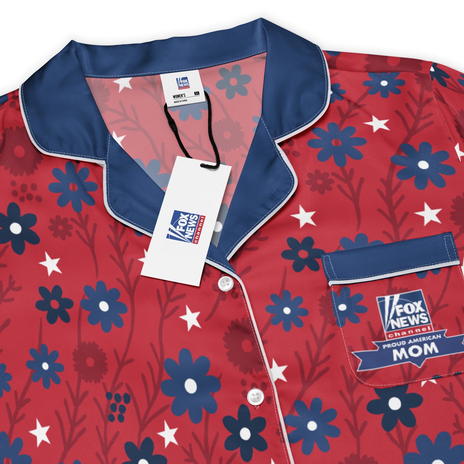 A neatly folded stack of FOX News apparel including the Proud American Mom pajama top on a warm wooden surface.