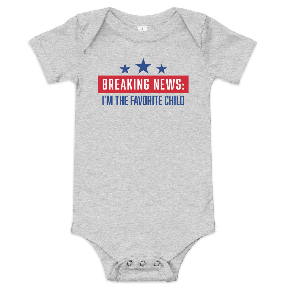 A FOX News Breaking News baby bodysuit in grey, presented in a clean American suburban nursery setting.