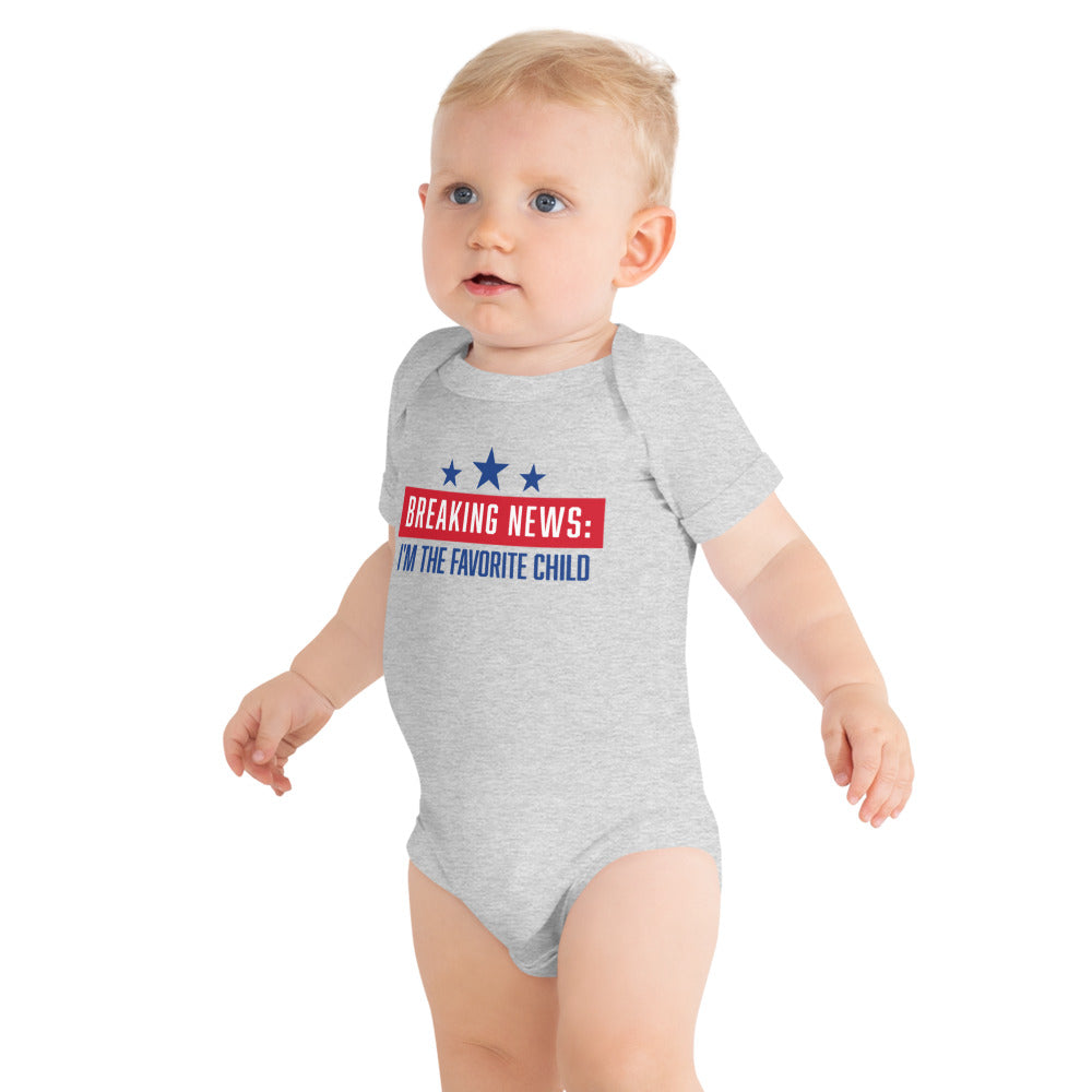 A young baby wearing the FOX News Breaking News bodysuit while playing in a modern American living room.