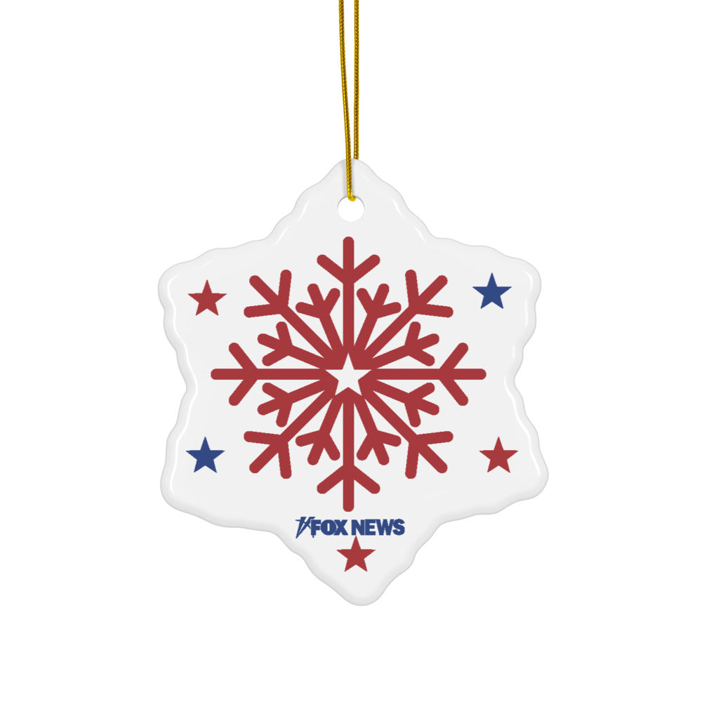 A snowflake-shaped ceramic ornament with the FOX News logo displayed against a festive, suburban holiday background.