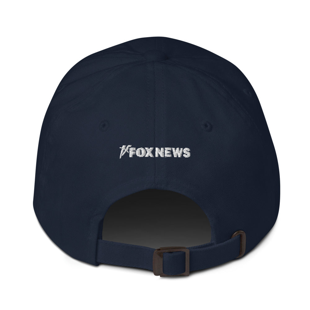 A clean lifestyle view of the cranberry FOX News dad hat resting on a wooden table in a modern American living room.