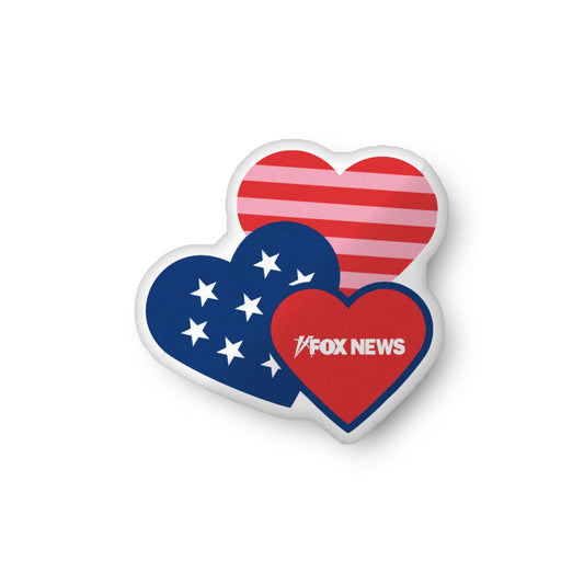 A soft *FOX News* Hearts Pillow resting on a neutral-colored sofa in a clean, modern American living room.