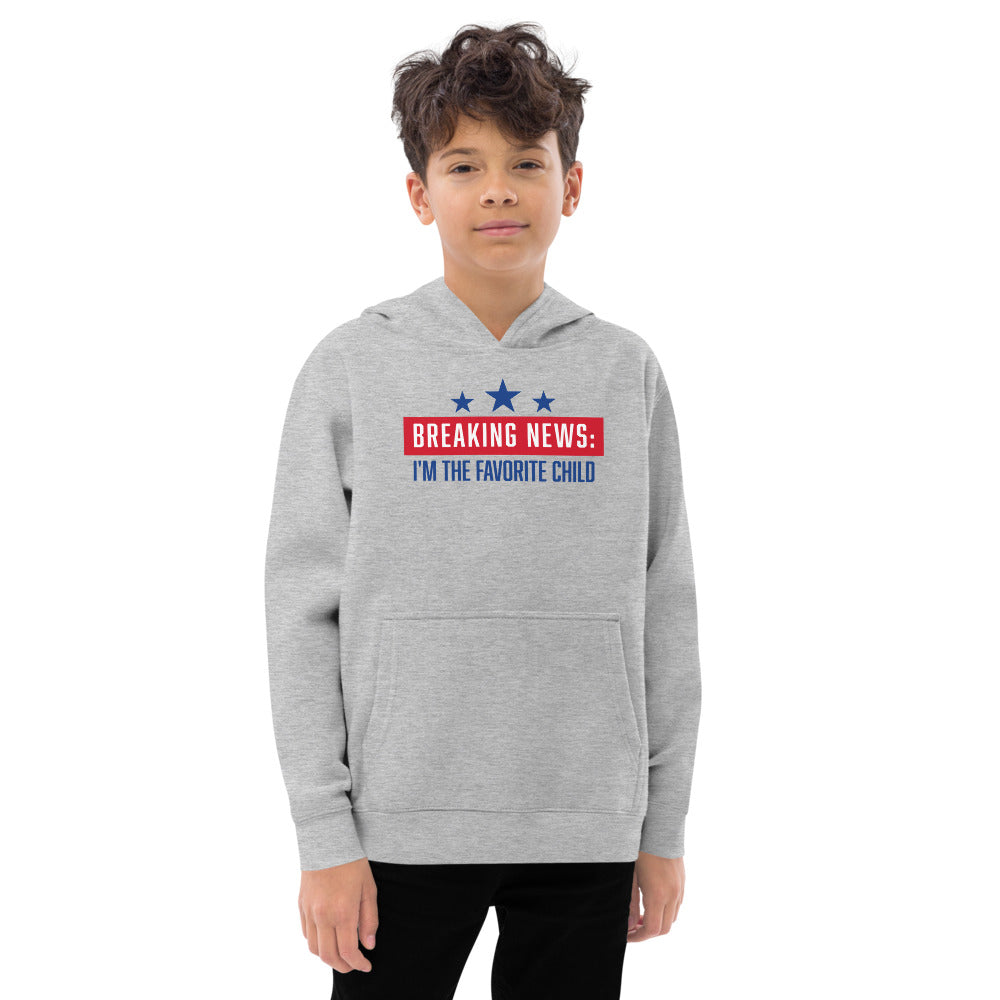 A young fan in a backyard setting wearing the FOX News Breaking News Kids Hoodie, showcasing the comfortable fit and patriotic design.
