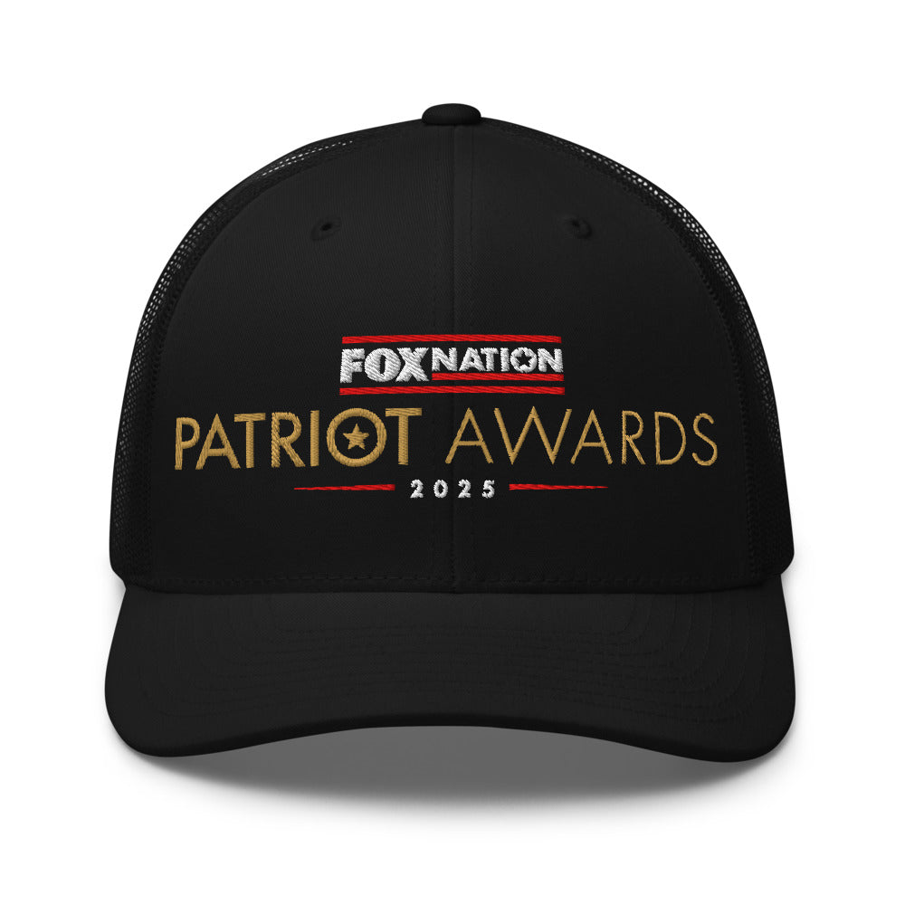 Front view of the black FOX Nation Patriot Awards 2025 Trucker Hat showing the crisp logo in a clean, modern American home setting.
