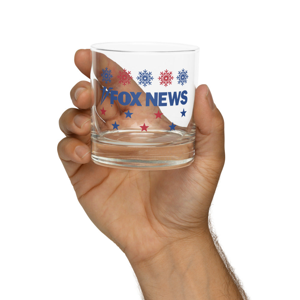 The FOX News holiday glassware being used for a drink in a modern, cozy backyard setting.