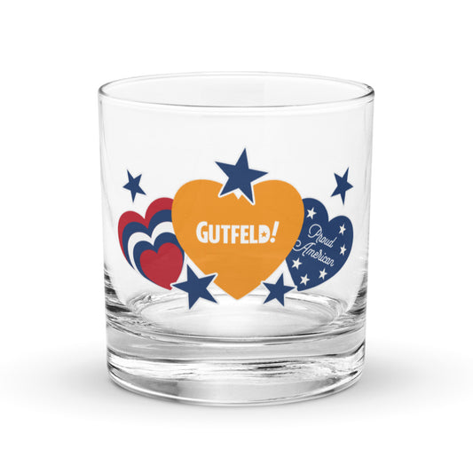 A 10.5 oz *Gutfeld!* rocks glass featuring the *Proud American* hearts and stars design on a clean wooden table.
