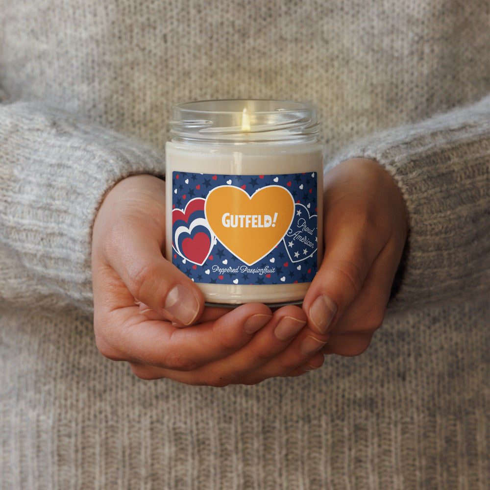 The Gutfeld! Proud American Hearts and Stars 9oz Peppered Passionfruit candle with its lid off, showing the white wax and wick.