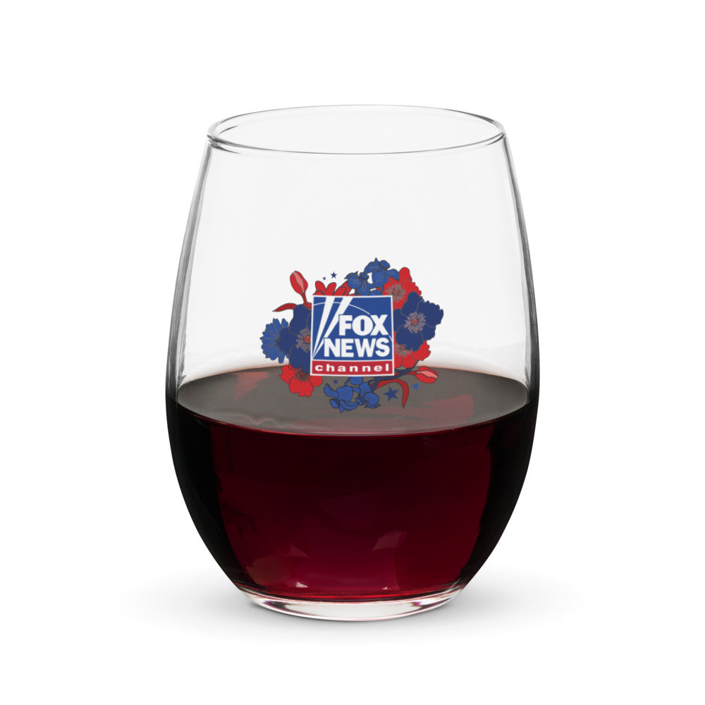 A clear 15-ounce stemless wine glass featuring the Proud American Mom design with crisp FOX News branding, set against a modern American living room background.