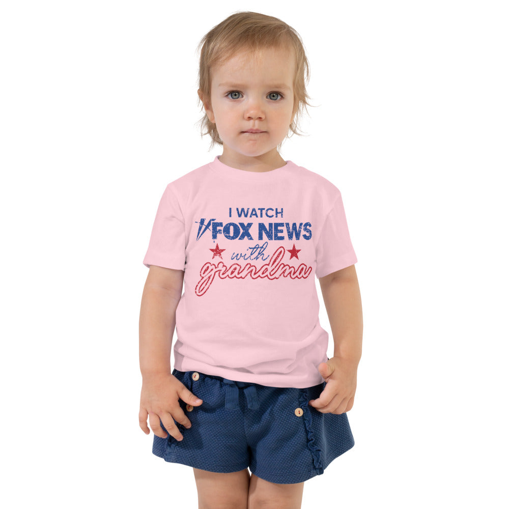 A young child wearing the FOX News toddler shirt while sitting in a modern living room setting.