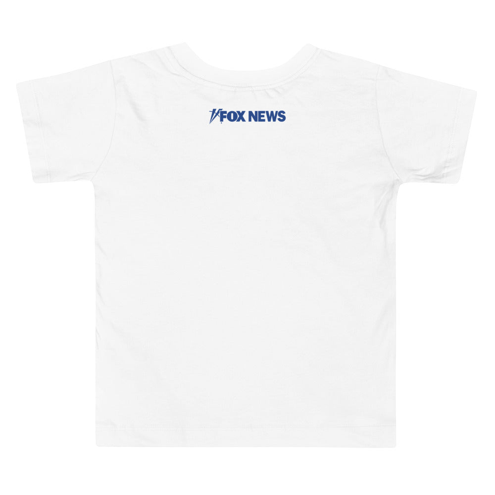 A toddler wearing the FOX News Breaking News T-Shirt in a bright, modern American home setting.