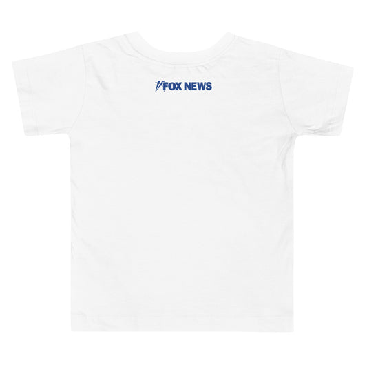 A toddler wearing the FOX News Breaking News T-Shirt in a bright, modern American home setting.