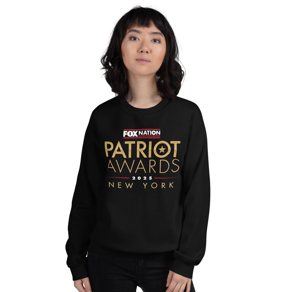 A loyal viewer relaxing in a modern American living room wearing the royal blue Patriot Awards 2025 pullover.