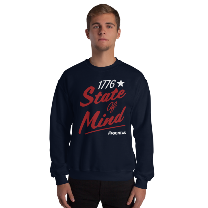 A woman wearing the gray FOX News 1776 State Of Mind crewneck in a clean home setting.
