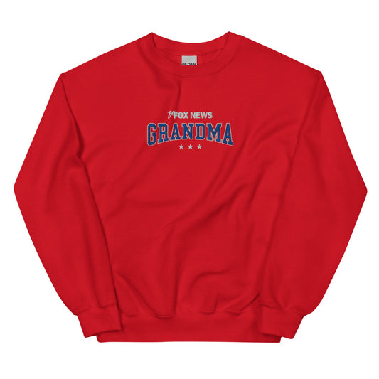 A red FOX News Grandma sweatshirt featuring the FOX News logo and Grandma graphic, displayed in a bright and comfortable American living room setting.-0