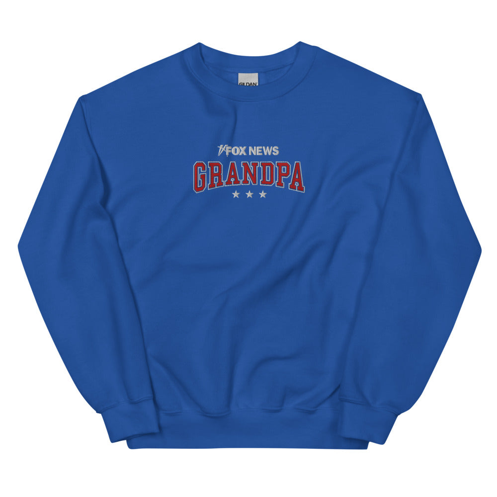 A patriotic grandfather wearing the royal blue FOX News Grandpa sweatshirt in a comfortable American home setting.
