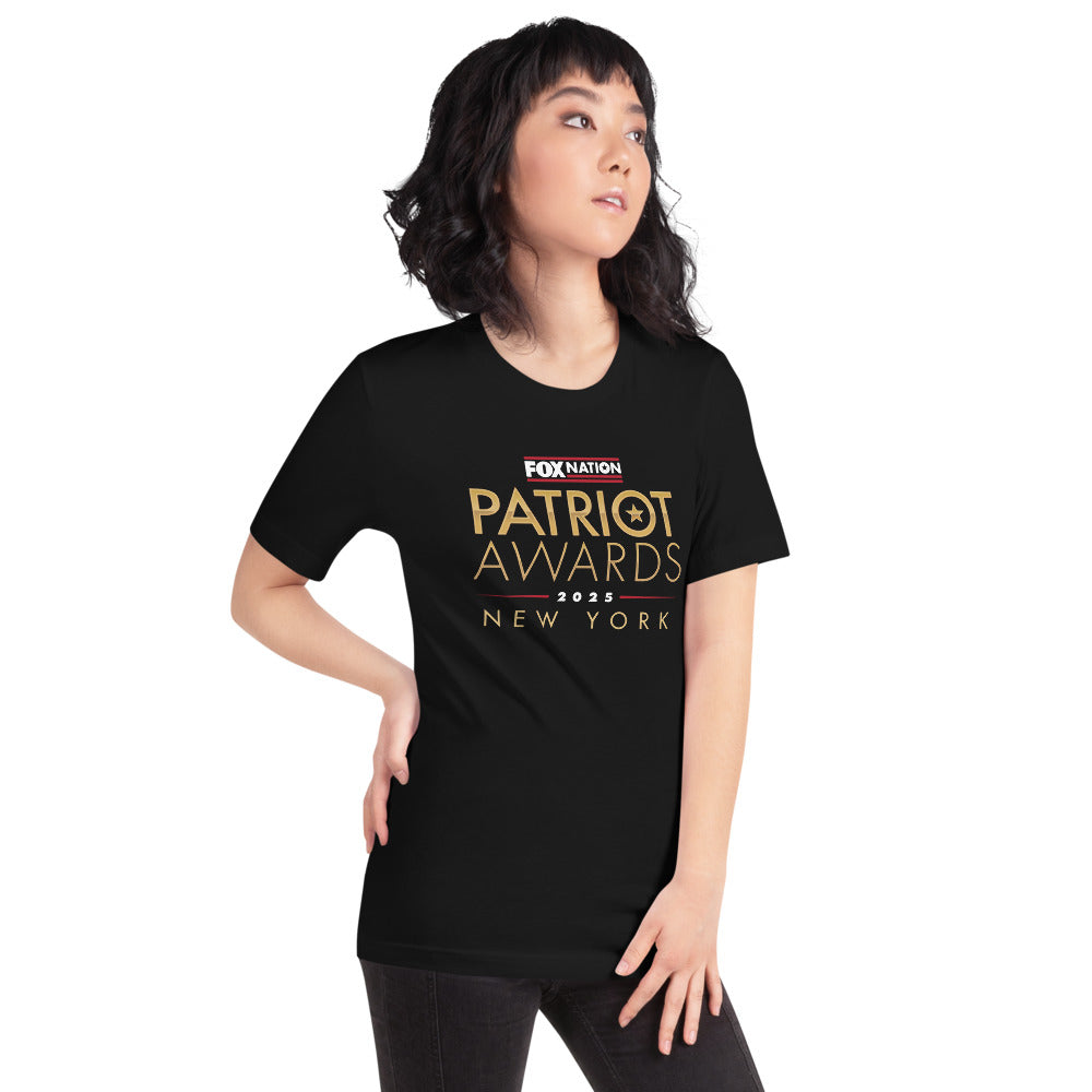A woman in a modern American living room wearing the FOX Nation Patriot Awards 2025 T-shirt.