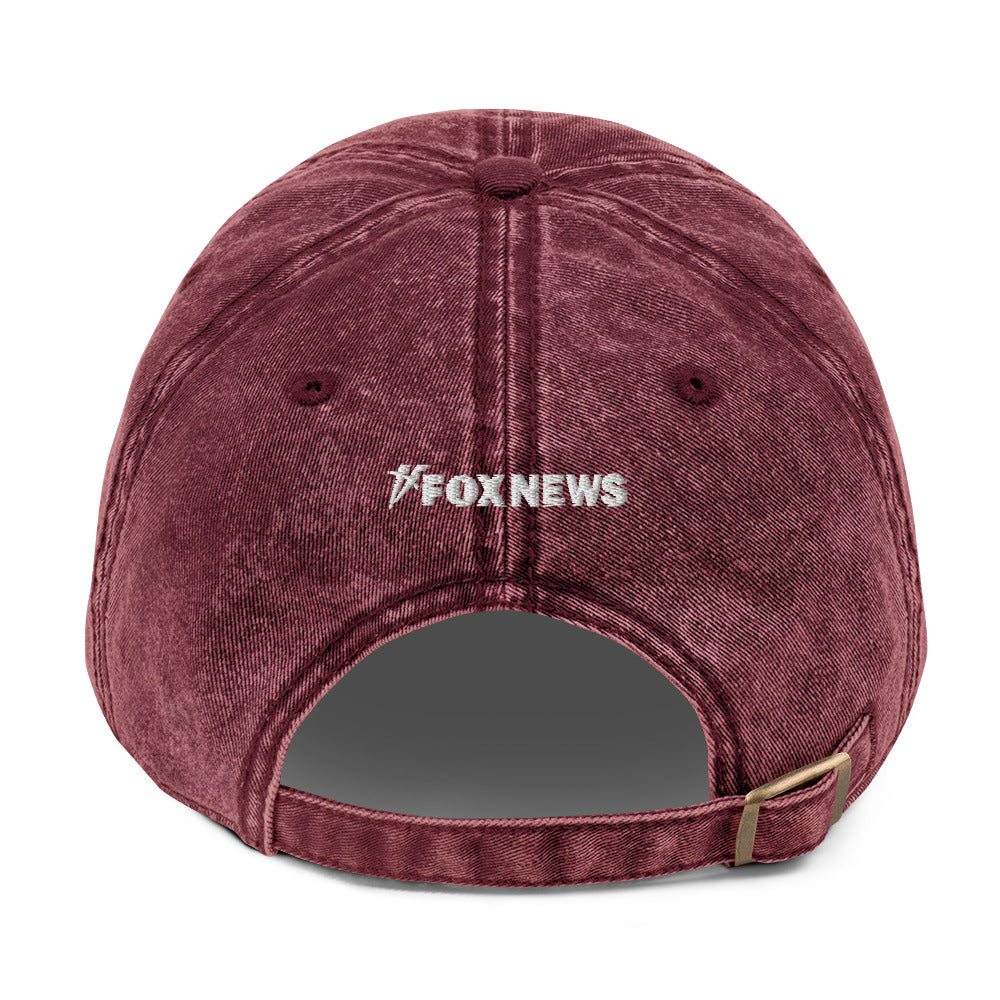 An outdoor lifestyle perspective of the FOX News Proud American Denim Hat resting on a porch railing.