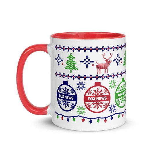 A crisp white FOX News Holiday Two-tone Mug with a festive colored interior, placed on a clean wooden kitchen table in a warm American home setting.