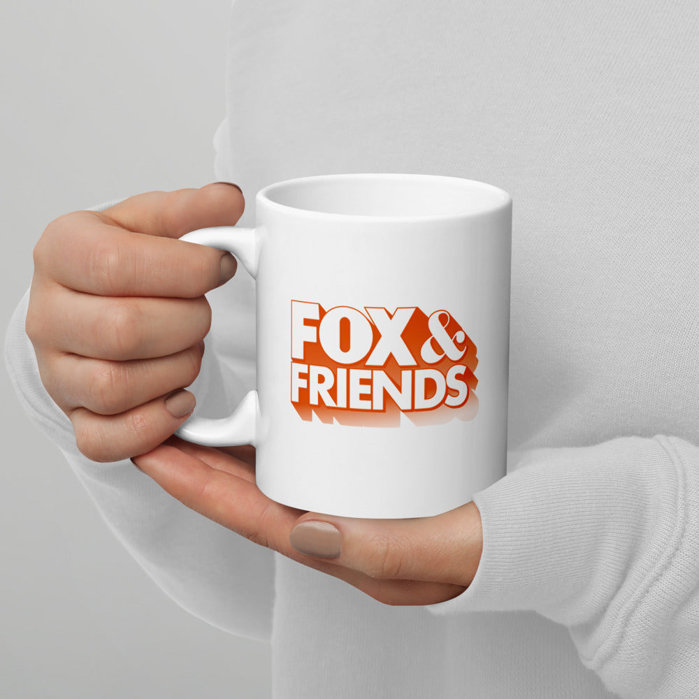 A FOX & Friends coffee mug filled with hot coffee next to a morning newspaper on a tidy living room side table.