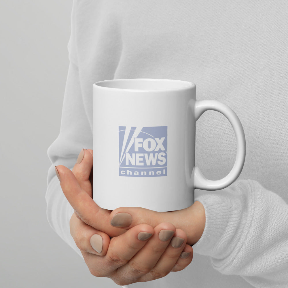 The 15-oz FOX News Under His Wings mug displayed beside a warm cup of coffee, highlighting its generous size and comfortable handle.