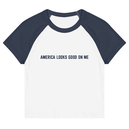 Women's fitted raglan baby tee featuring the red, white, and blue FOX News logo and America Looks Good On Me text across the chest, displayed against a clean American living room setting.