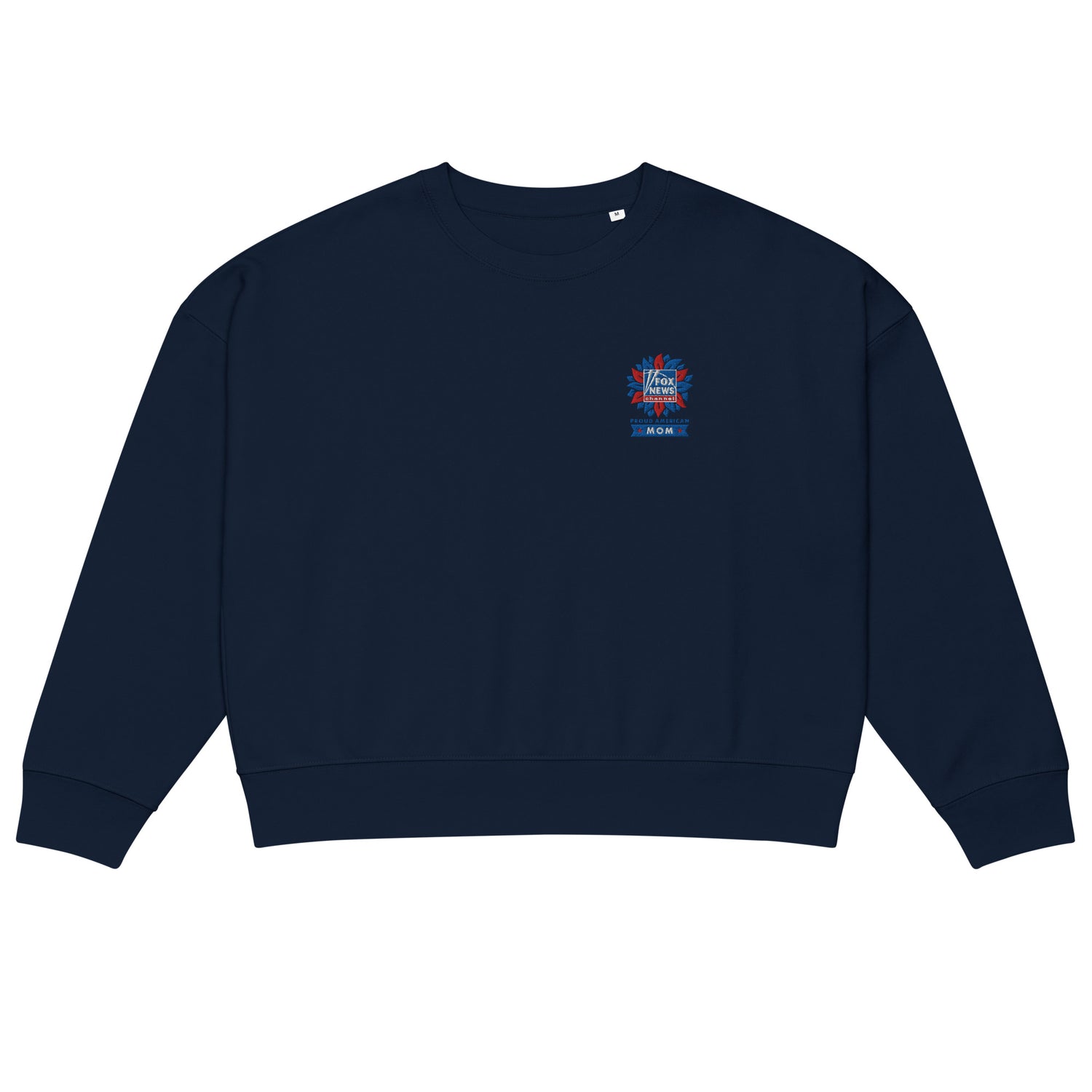 A modern American living room setting featuring the FOX News Proud American Mom embroidered sweatshirt folded neatly on a neutral-toned sofa.